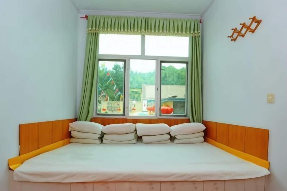 Quarto com cama, janela com cortinas e um suporte fixado na parede.