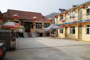 A building with a red tiled roof, a covered entrance, and a staircase leading to the main entrance. - Dalian Bingyugou Xiaomu Farmstay (Zhuanghe)