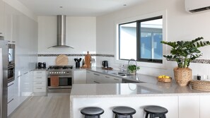 A modern kitchen with stainless steel appliances, a large window, and a central island with stools. - Stunning Beach Views Pet Friendly Dromana Retreat (Dromana)