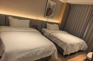 Habitación de hotel con dos camas, cabecero, una obra de arte colgada en la pared y ventana con cortinas.