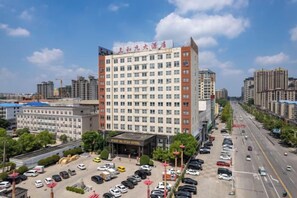A multi-story hotel with a parking lot and a street view. - Sanheyuan Hotel (Zhecheng Future Avenue Branch) (Zhecheng)