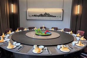 A round conference table with chairs, a central decorative piece, and a framed artwork on the wall.
