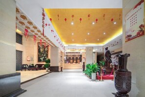 A hotel lobby with a reception desk, seating area, and decorative elements. - Sanheyuan Hotel (Zhecheng Future Avenue Branch) (Zhecheng)