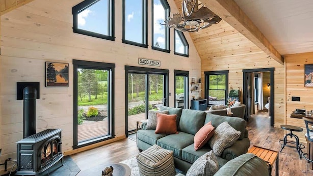 Un salón amplio con un sofá verde grande, una chimenea y un cartel que dice "SADDLEBACK".