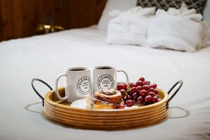Un plateau avec deux tasses, une pâtisserie et des raisins disposés sur un lit.
