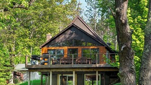 Une cabane dotée d’un balcon, d’une terrasse en bois et offrant une vue sur la forêt environnante.