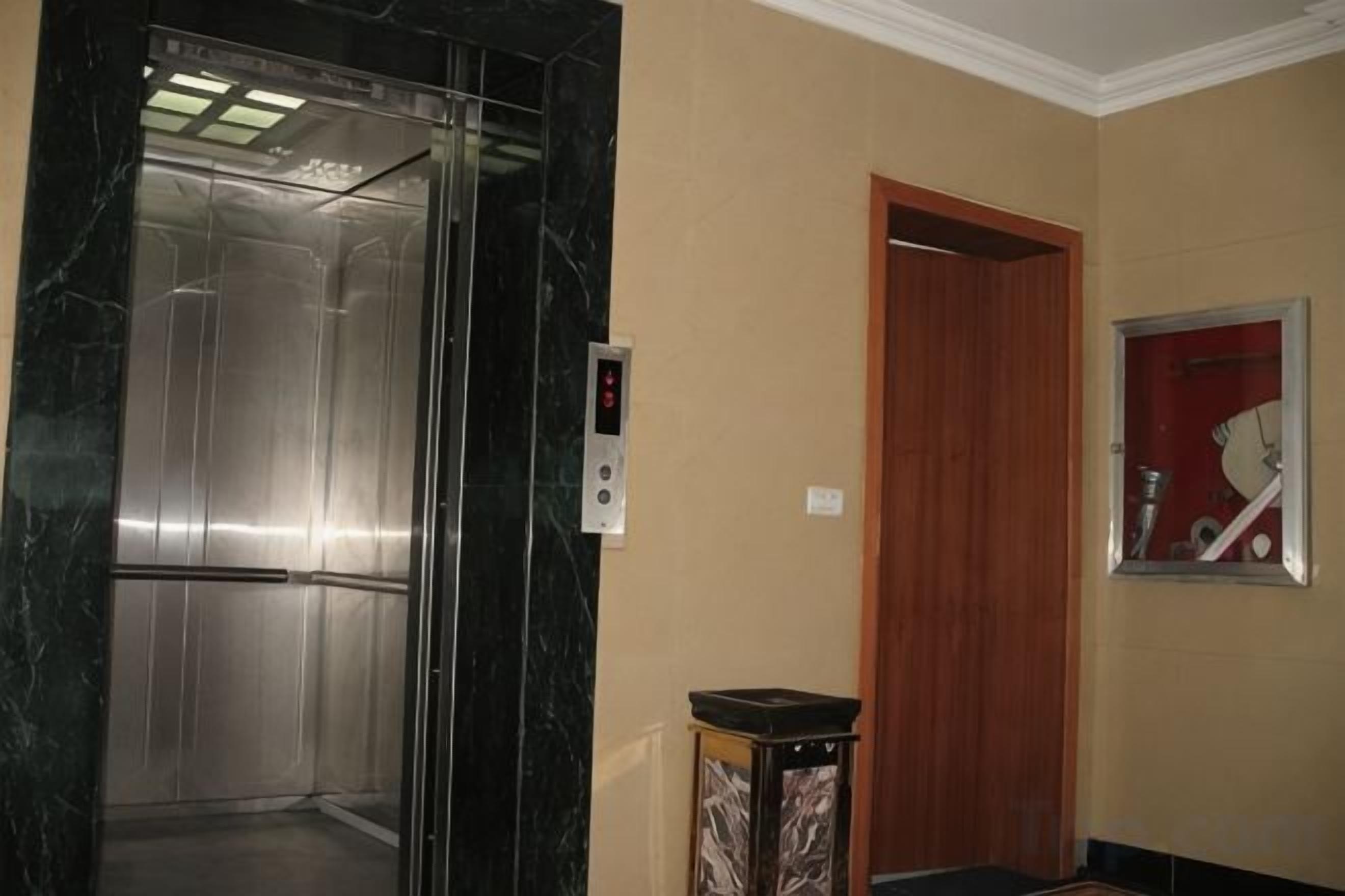 Un ascensor con panel de control, una puerta de madera y un reloj fijado a la pared.