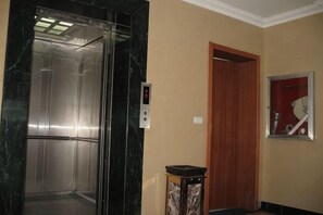 An elevator with a control panel, a wooden door, and a wall-mounted clock. - Libo Dapeng Business Hotel (Libo Ancient Town) (Libo)