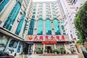 Un hotel con una entrada amplia, varias ventanas y un letrero con caracteres chinos.