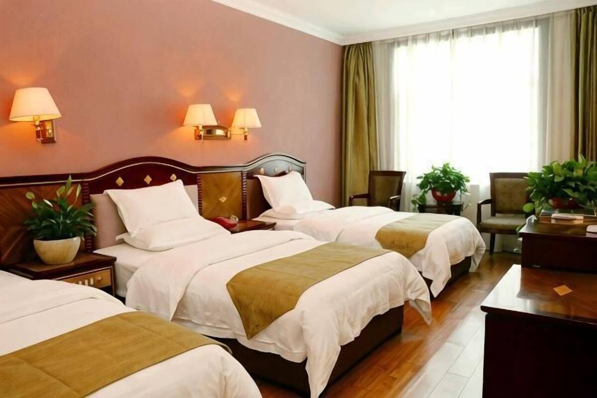 A hotel room with two beds, bedside lamps, a desk, and a chair.