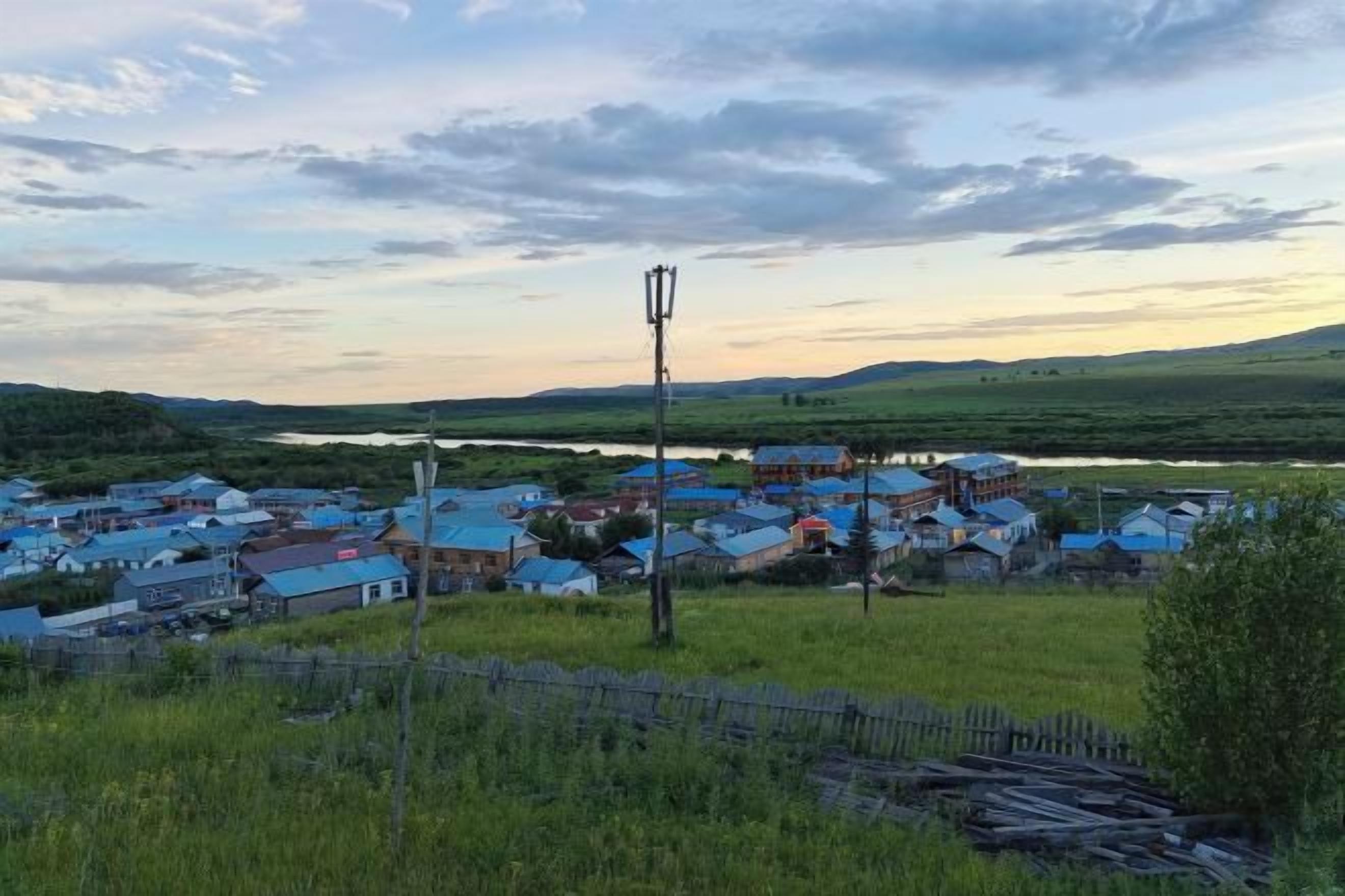 A rural village with houses and a river in the background.