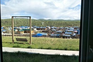 A view of a rural area with a wooden bench, a metal frame structure, and a row of houses with blue roofs.