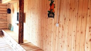 Interior de madera con suelo y pared de madera, y una maceta colgante con follaje.