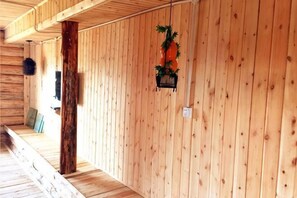 A wooden interior with a wooden floor, a wooden wall, and a hanging planter with greenery.