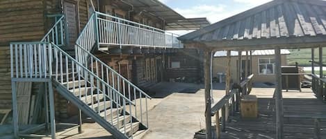 A wooden building with a staircase, a covered outdoor area, and a metal railing.