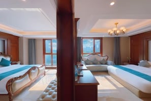 A hotel room with two beds, a sitting area, and a large window.