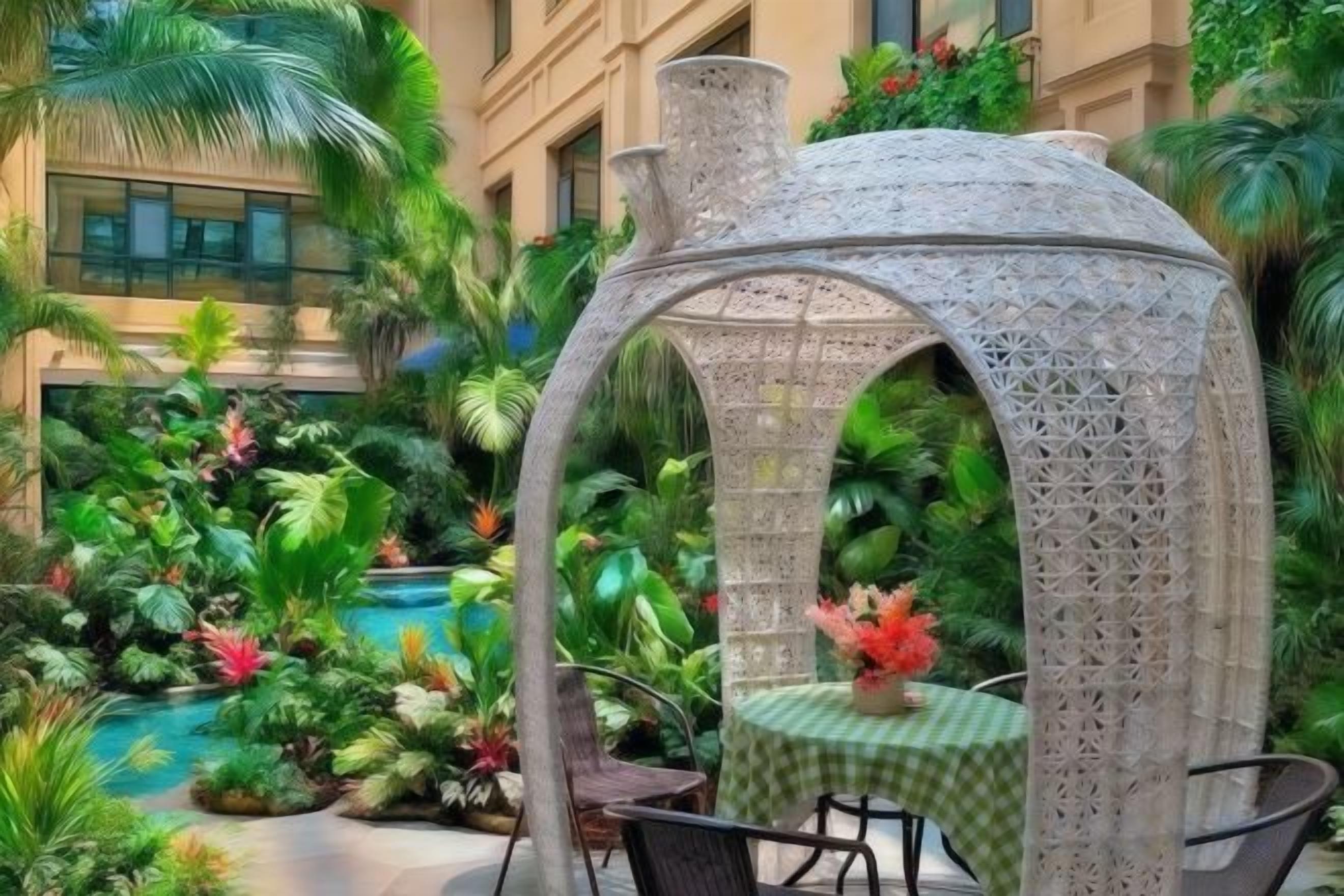 A gazebo with intricate lattice work, surrounded by lush tropical plants and a small pool.