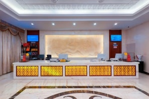 A reception desk with a modern design, featuring a marble floor and a large, illuminated wall display.