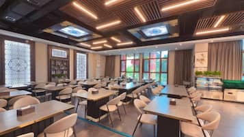 A conference room with multiple tables and chairs, a long table with a projector, and a large window with a view.