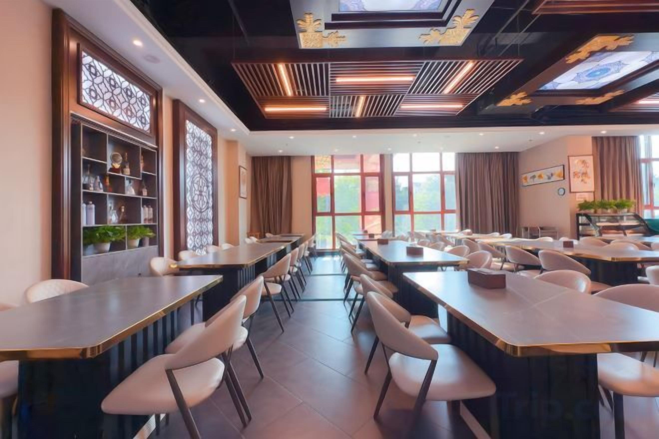 Un restaurant amb taules llargues i caires, un sostre amb llums decorades, i grans finestres.