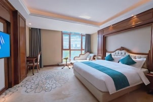 Una habitación de hotel con una cama grande, un escritorio, una silla y un televisor.