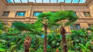 A building with multiple windows and a lush garden with tall palm trees. - Mintai Hot Spring Holiday Hotel (Zibo)