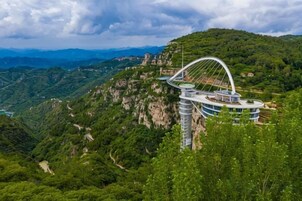 Un hotel con una arquitectura curva distintiva sobre una colina, rodeado de vegetación exuberante y un paisaje montañoso.