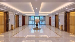A spacious lobby with a polished floor, a central decorative vase, and a large window providing a view of the outdoors. - Mintai Hot Spring Holiday Hotel (Zibo)