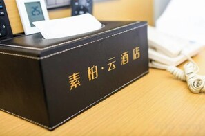 A black box with Chinese characters on a wooden surface, a white tissue box, and a white telephone handset.
