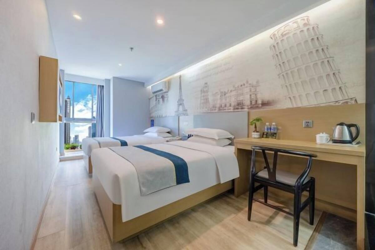 A modern hotel room with a bed, a desk, and a chair.