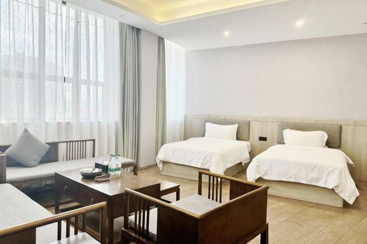 A hotel room with two beds, a sofa, a dining table, and chairs.
