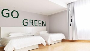 A modern hotel room with a large bed, a headboard, and a wall with the words 'GO GREEN'. - Homeinn Pebble Hotel (Hami Railway Station Bayi North Road) (Hami)
