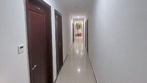 Un long couloir étroit, avec des portes de chaque côté, qui mène à une pièce au bout.