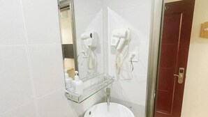 Une salle de bain équipée d’un lavabo, d’une douche à parois de verre, d’un sèche-cheveux et d’un miroir.
