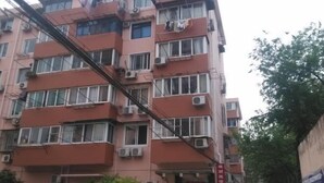 Un immeuble à plusieurs étages doté de balcons, de climatiseurs et d’une devanture visible au niveau du rez-de-chaussée.