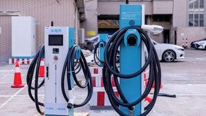 Estaciones de carga para vehículos eléctricos en un estacionamiento al aire libre, con un edificio de fondo.
