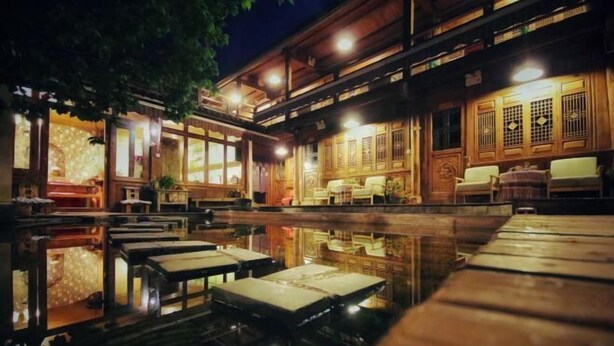 A traditional wooden building with a reflective pool and seating areas.