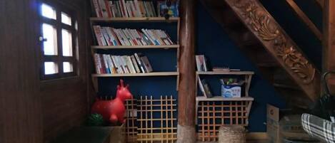A room with wooden bookshelves, a wooden bench, a red toy, and a wicker basket.