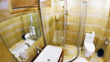 A bathroom with a glass-enclosed shower, a sink, and a toilet.