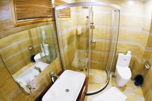 A bathroom with a glass-enclosed shower, a sink, and a toilet. - Mrs. Sha's Living Room Inn (Jianchuan)