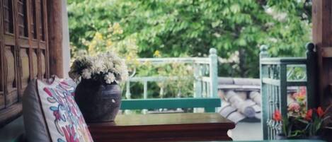 A wooden bench with a potted plant and a cushion.