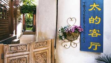 A wooden door with intricate carvings, a blue sign with yellow text, and a hanging flower basket.