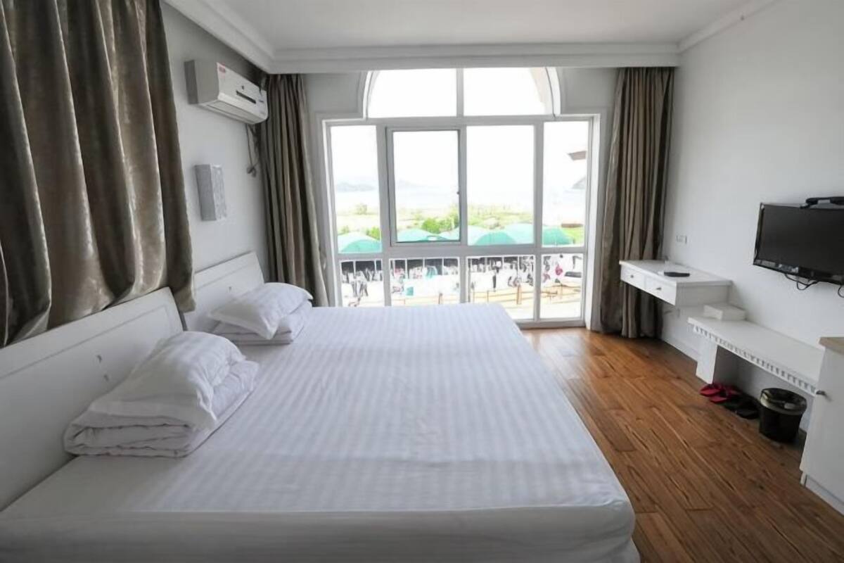 Habitación de hotel con una cama grande, televisión, balcón con vistas y escritorio con silla.