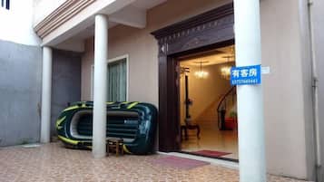 A hotel entrance with a sign indicating availability, a staircase leading inside, and a green suitcase on the ground.