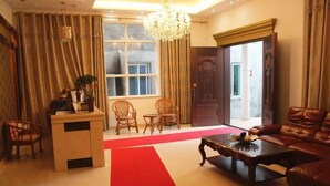 A hotel lobby with a reception desk, leather sofa, and a red carpet leading to a door. - Peach blossom island bay longines farmhouse (Zhoushan)