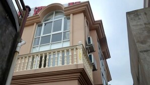 A building with a large arched window and a balcony with balustrades. - Peach blossom island bay longines farmhouse (Zhoushan)