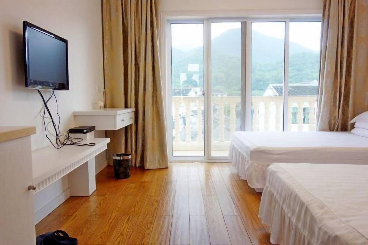 Habitación de hotel con un ventanal grande, una televisión, un escritorio y dos camas.