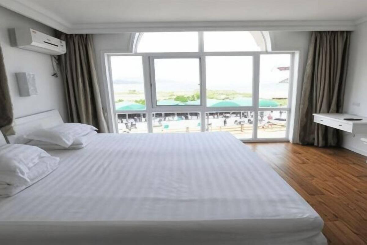 Habitación de hotel con una cama grande, vista al área de la piscina y puerta corredera al exterior.