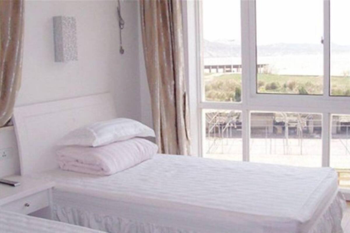 Un dormitorio con cama, mesita de noche y ventana con vistas a un puente y al paisaje.