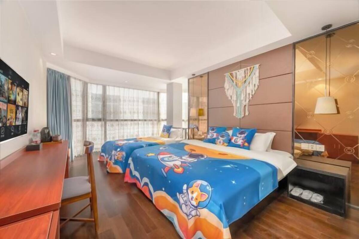 Quarto de hotel com uma cama grande, uma escrivaninha e vista para o exterior.